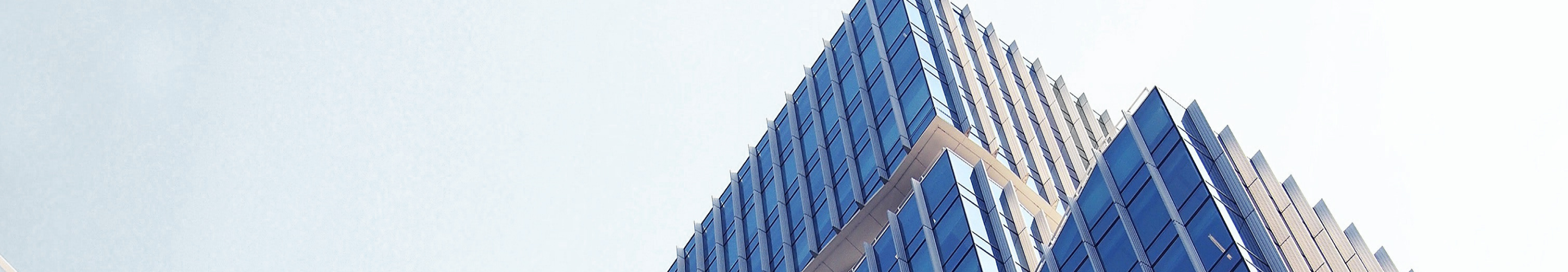 A bottom-up view of a modern office building on a clear, sunny day.