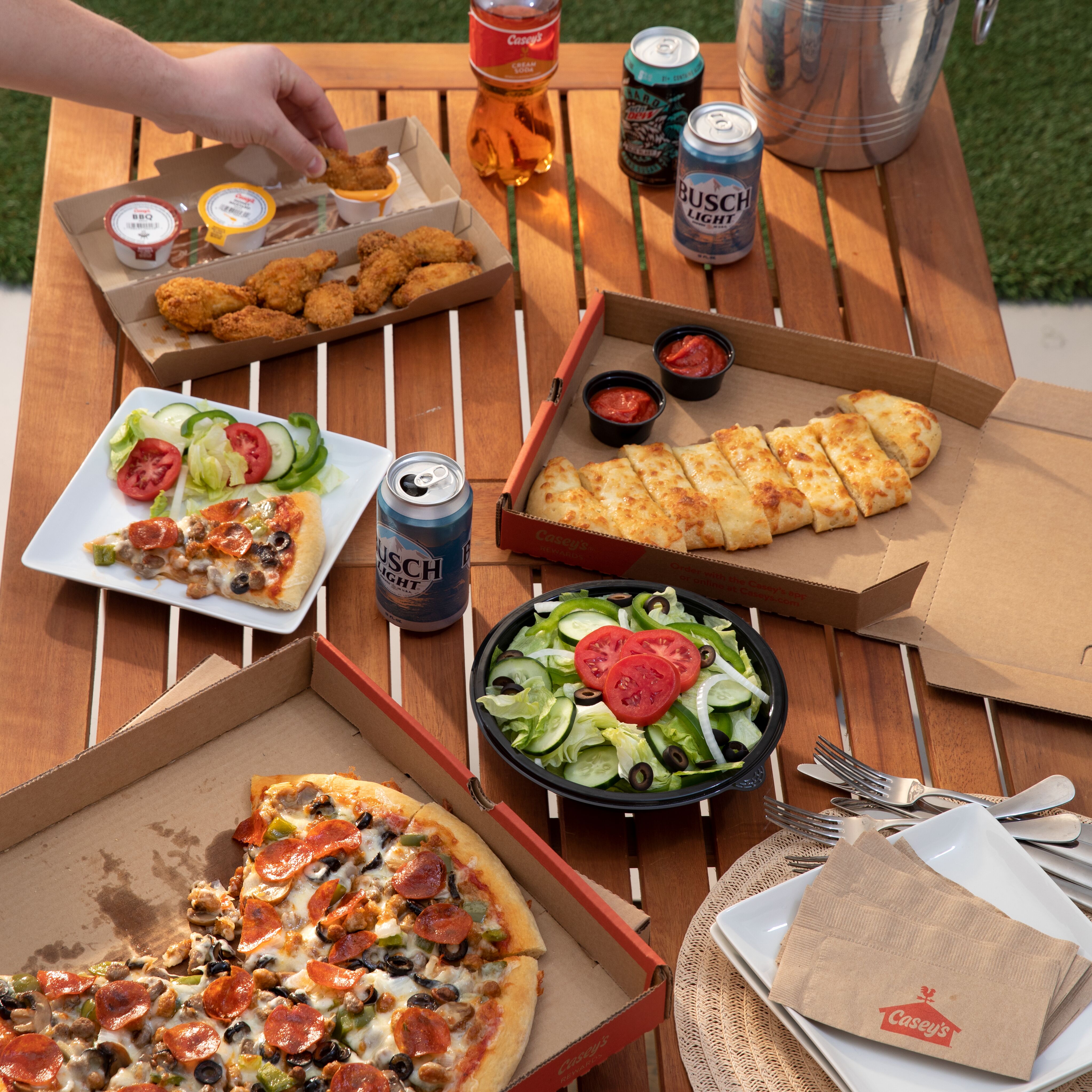 Pizza Party on Patio featuring cheesy breadsticks, salad, wings with ranch and buffalo sauce, supreme pizza and drinks