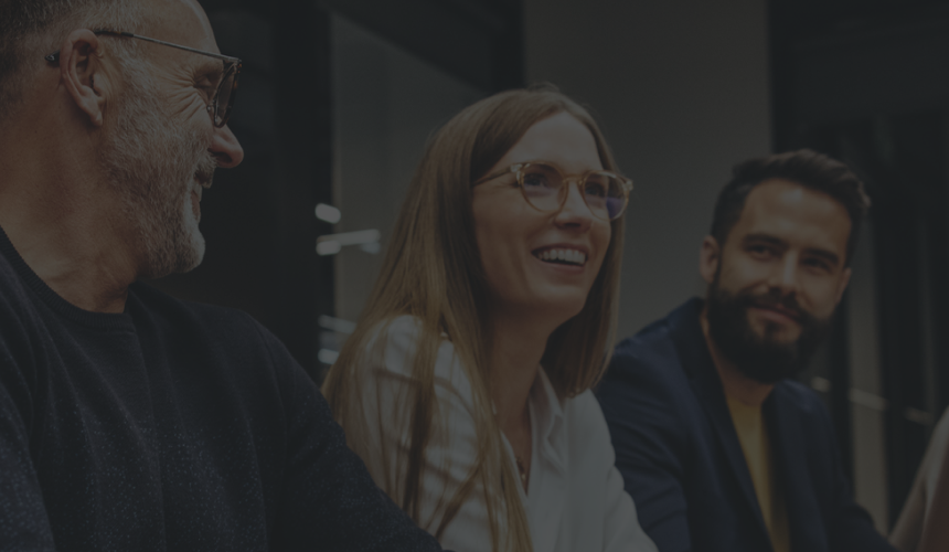 Three professionals sitting side by side and smiling.