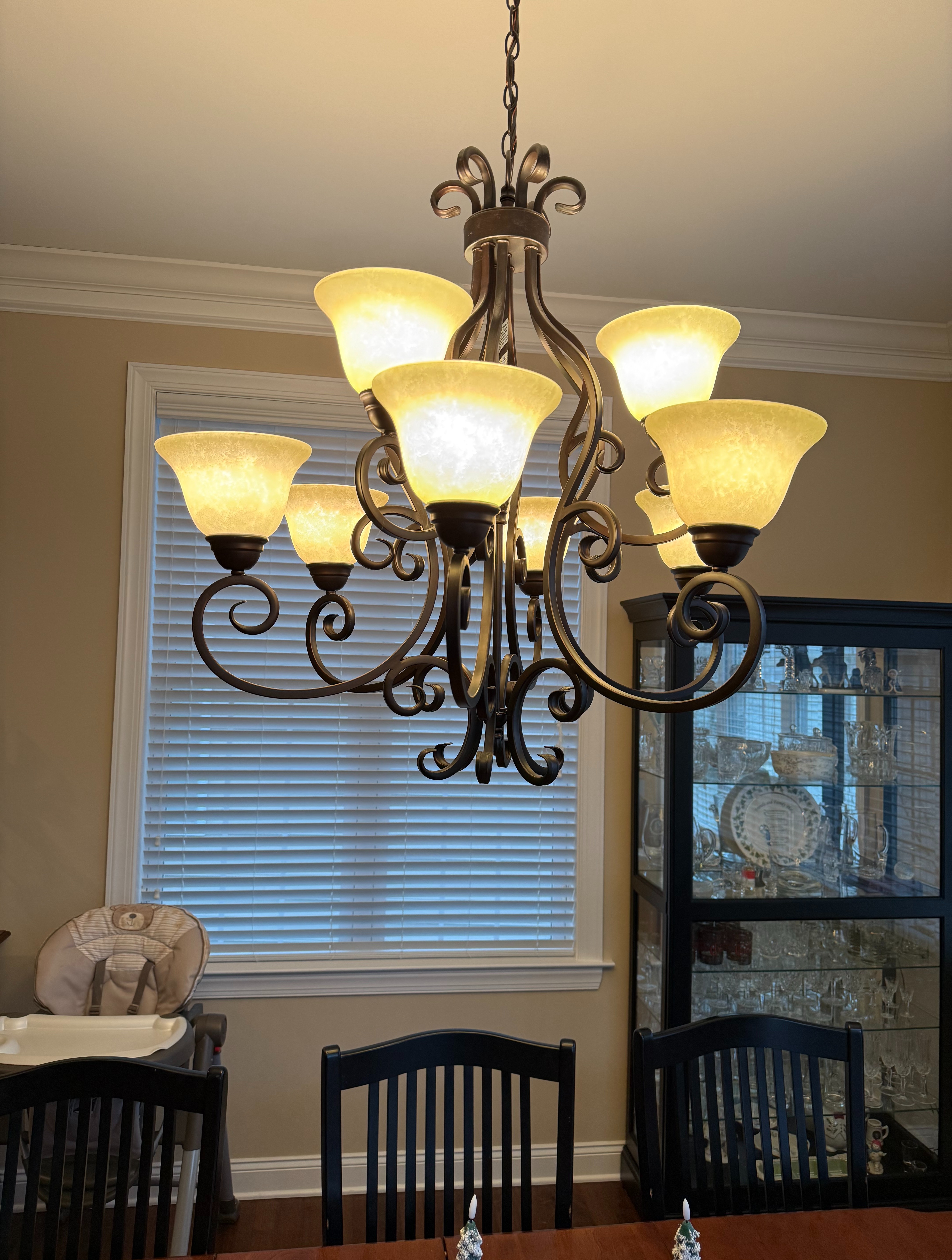 A nine-light scrollwork chandelier with amber glass shades installed by Thomas Edison Electric in a Norristown, PA dining room. The two-tier fixture adds warm, elegant lighting and serves as a centerpiece over the dining table.