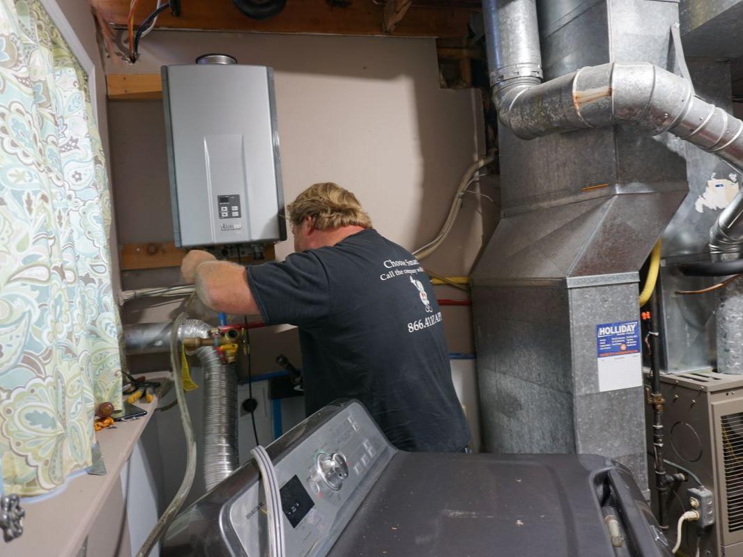 Plumber installs a tankless water heater on a wall