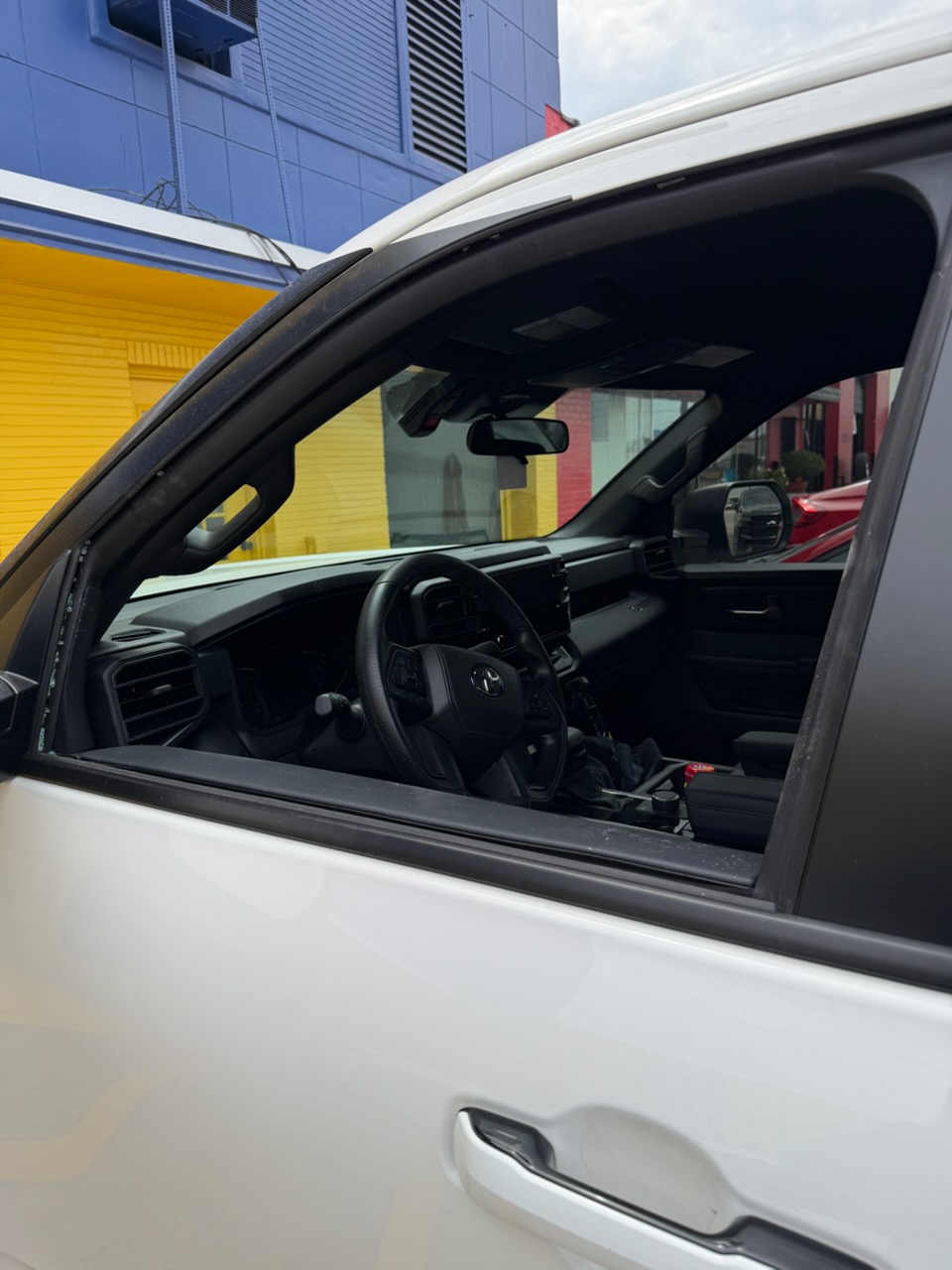 Close-up of the driver-side window opening on a white Toyota truck during auto glass service. The image highlights the type of side window glass work handled by Space Auto Glass.