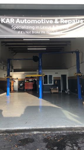 Front view of an automotive repair shop with open garage bay, vehicle lifts, and clean workspace. The signage above highlights the business name, while the interior shows professional equipment used for car maintenance and mechanical repair services.