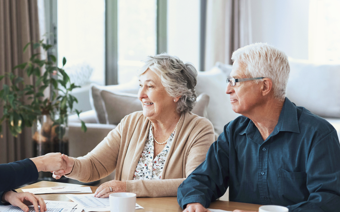 An elderly couple shaking hands with their financial advisor.