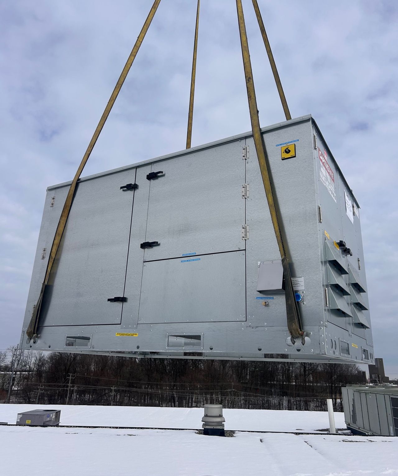Crane lowering a commercial RTU onto a roof