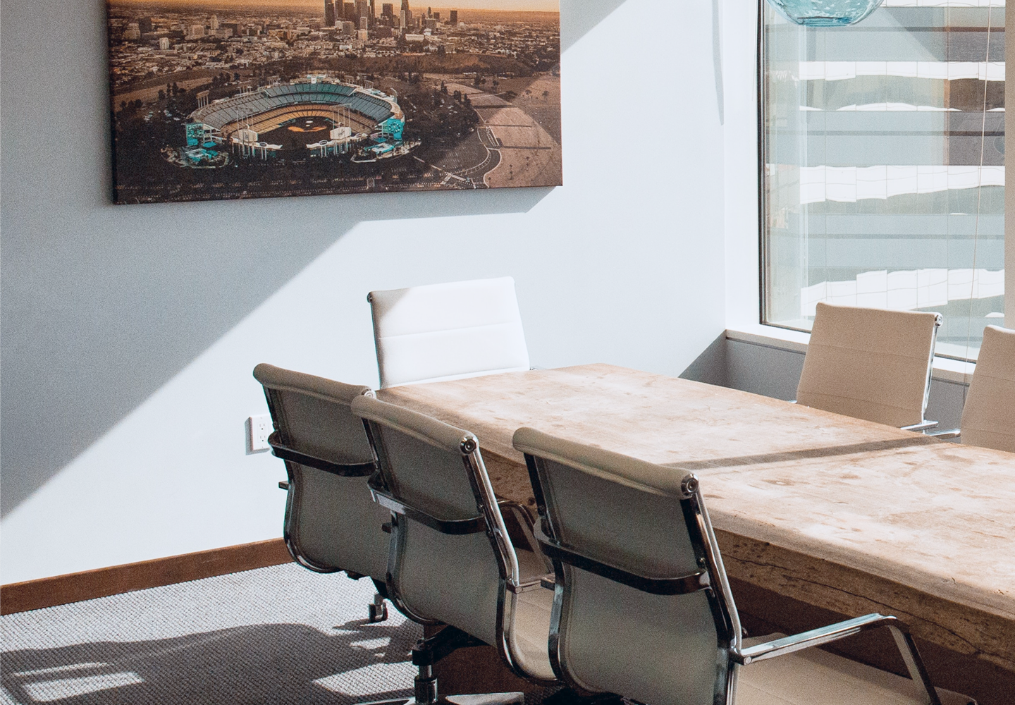 The sun shining through a large window into a modern boardroom.