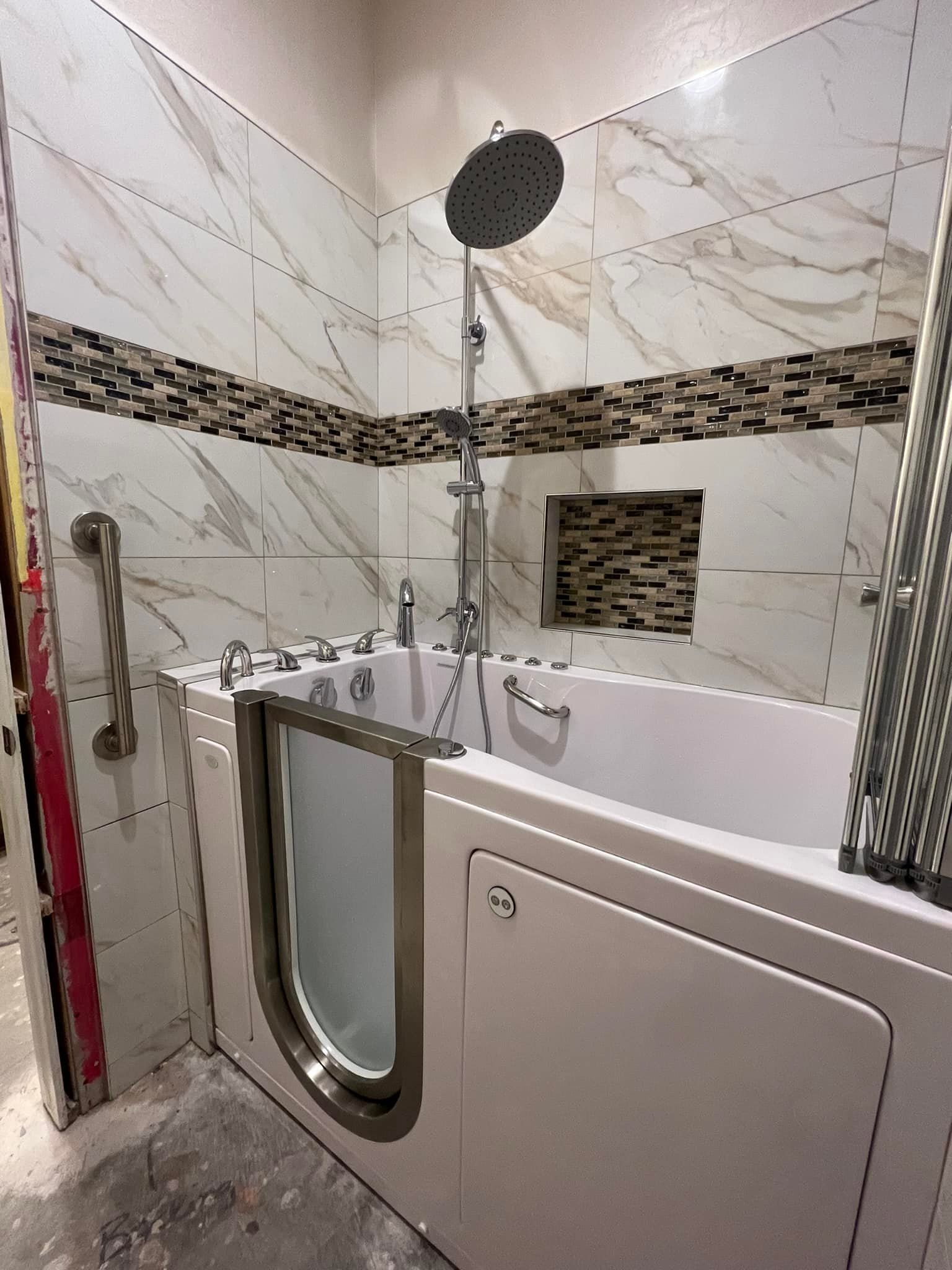 A newly installed walk-in bathtub with multiple jets is surrounded by white marble-patterned tiles a 