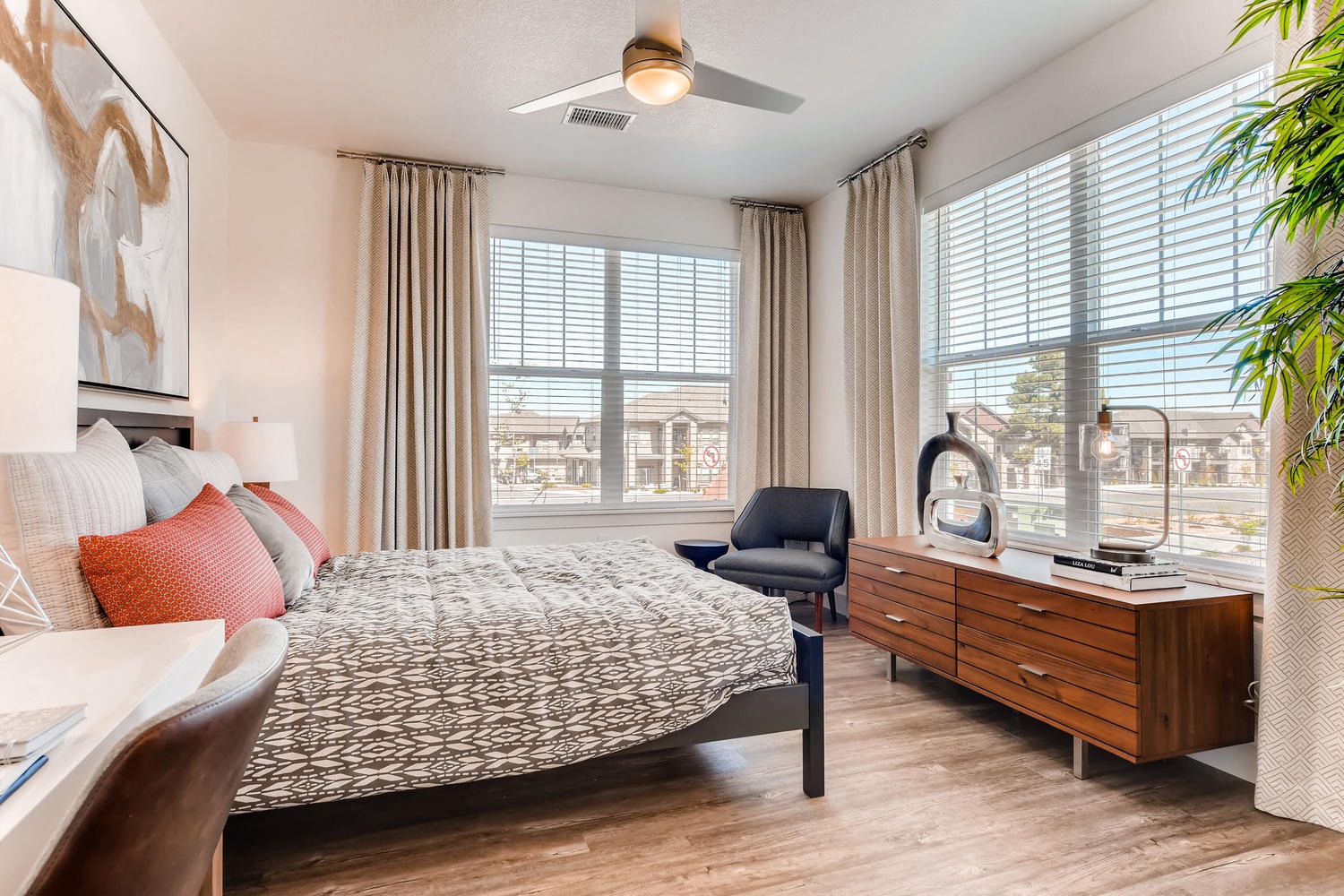 A bedroom with a bed, chair, and a ceiling fan.