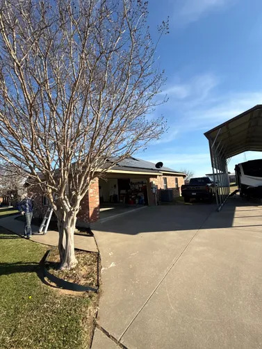 A residential home with a spacious driveway, detached carport, and mature tree showcases a well-maintained property, suitable for exterior inspection, roofing evaluation, or home improvement planning services.