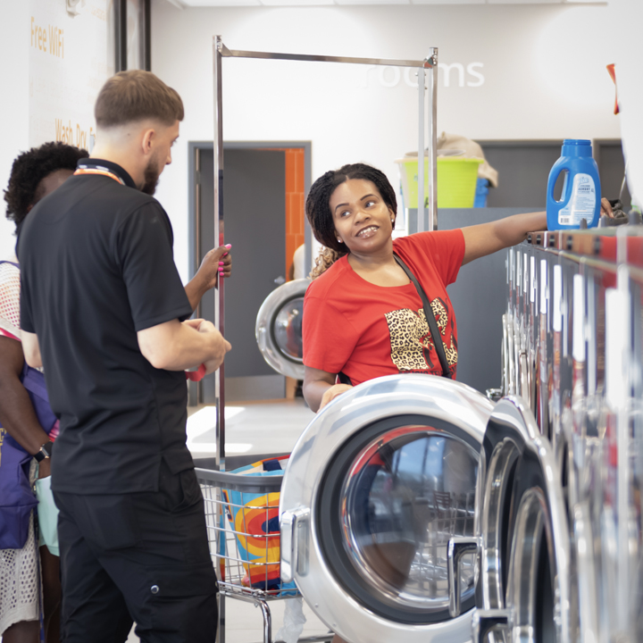 Speed Queen Laundry attendant helping a customer at a front-loading commercial washer. 