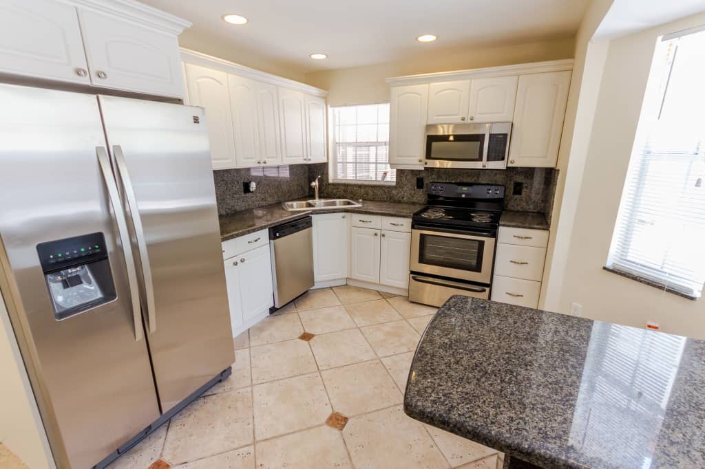 Stunning kitchen with stainless steel appliances, recessed lighting, and white cabinets at Invitation Homes South Florida.