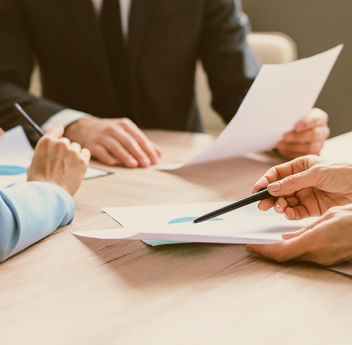 Close-up of three people examining papers on a desk.