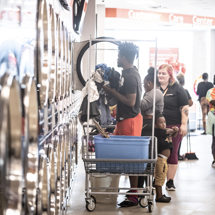 Customers moving laundry through a Speed Queen Laundry store using convenient rolling laundry carts. 