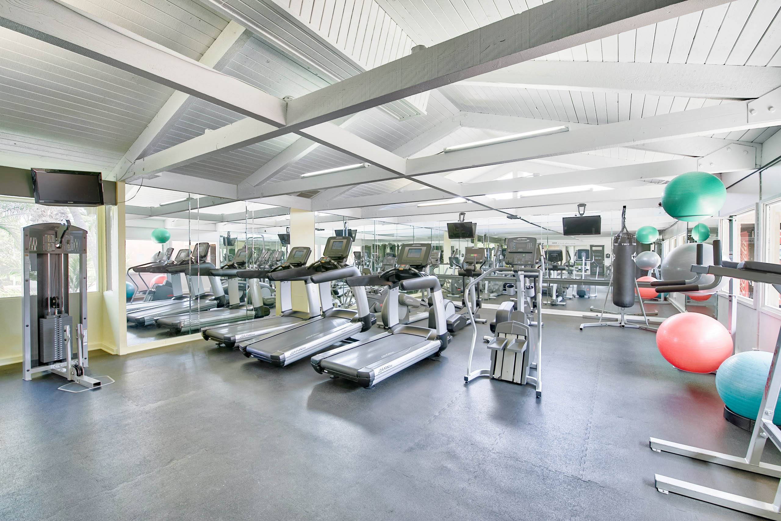 a gym with cardio equipment and weights on the floor