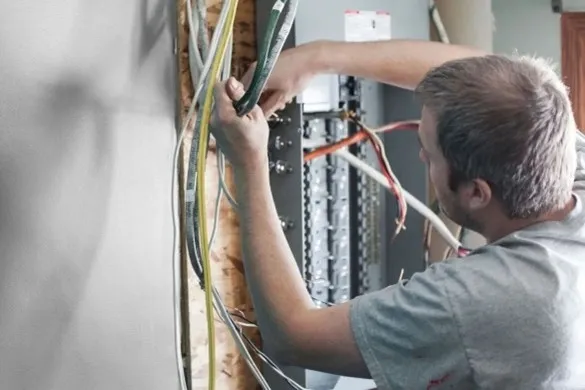 Electrician inspecting wiring inside an electrical panel.