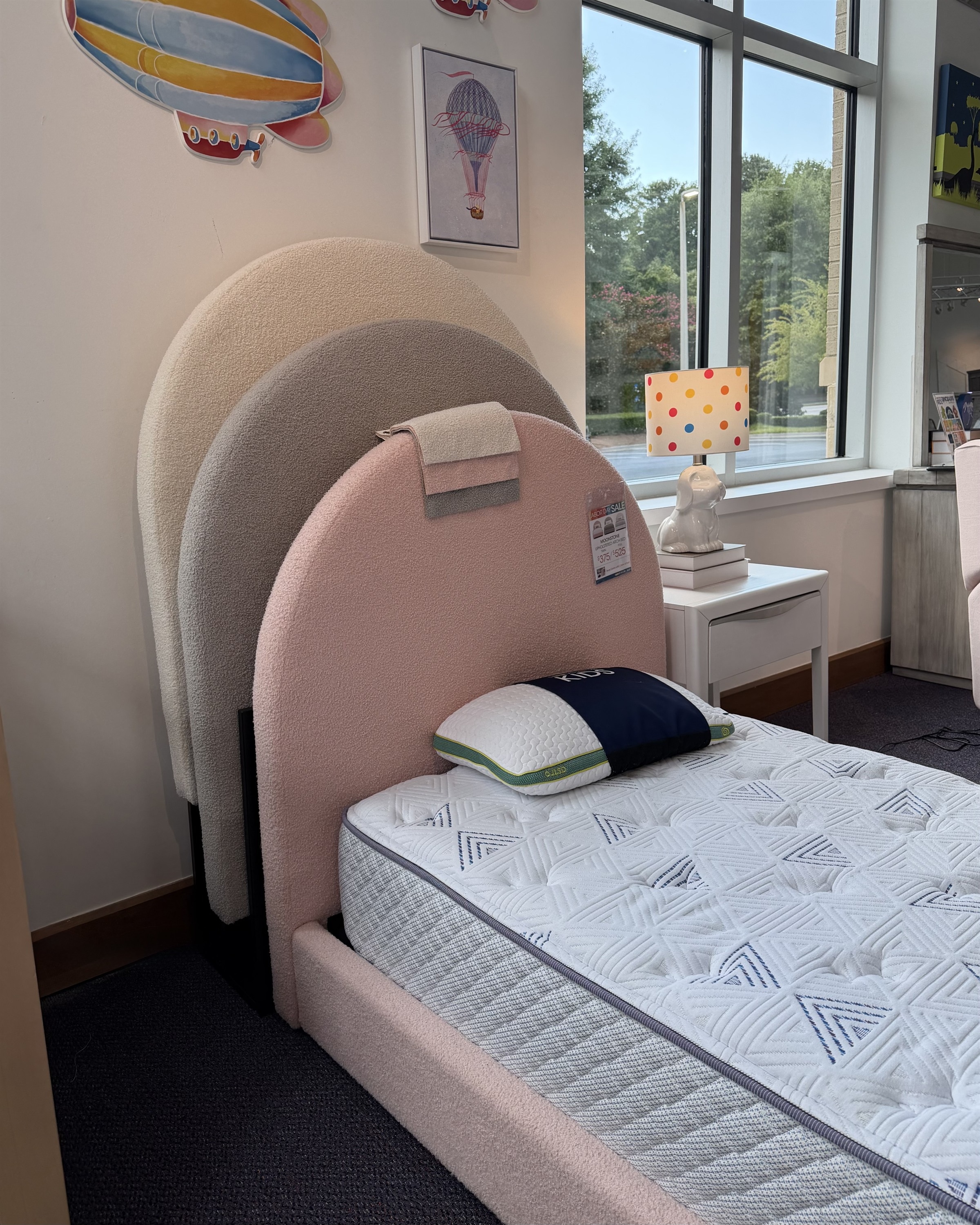 Pink boucle arched headboard twin bed with pull-out trundle in a hot air balloon themed room