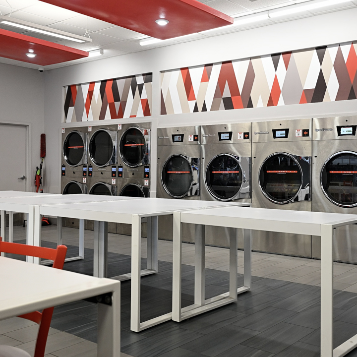 Bright, modern Speed Queen Laundry interior featuring rows of commercial washers and dryers with spa 