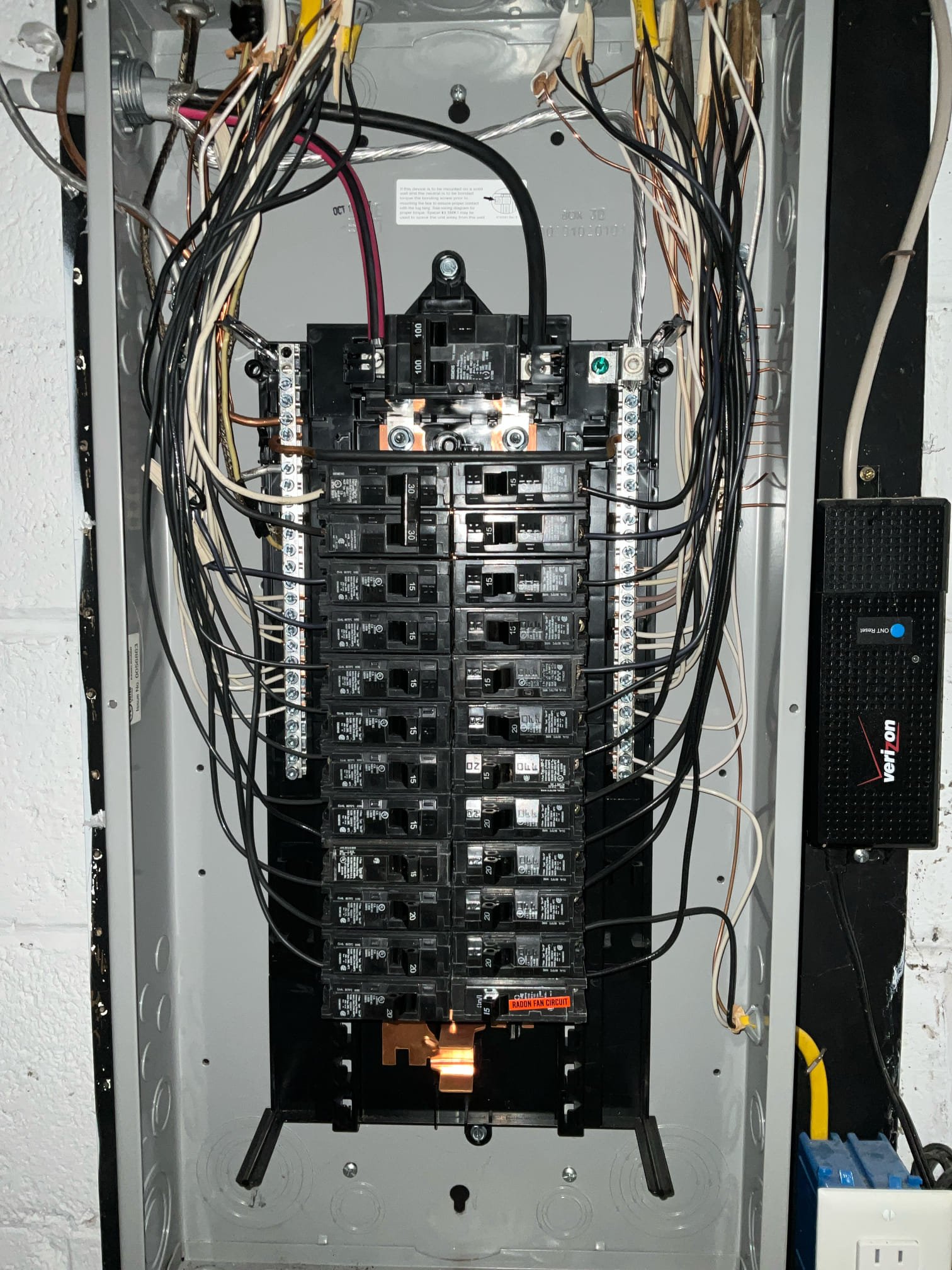 Thomas Edison Electric upgraded this 100-amp breaker panel in a Jenkintown, PA basement. The fully loaded panel includes a dedicated radon fan circuit labeled in red at the bottom, and a Verizon ONT is mounted alongside for the home's fiber internet connection.