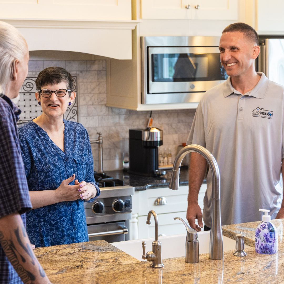 Homeowners and a Fiderio specialist review faucet selections and appliance layouts in a newly remodeled kitchen.