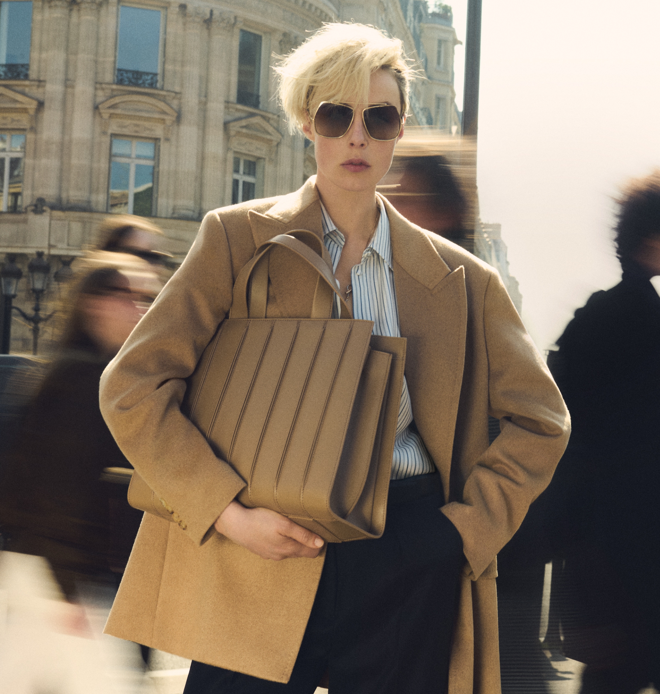 Das Model trägt den doppelreihigen Blazer Olimpia von Max Mara im Farbton Kamel zu dunkler Brille und Tasche Whitney Bag 7 von Max Mara aus Leder im Farbton Kamel mit vertikalen, hervorgehobenen Nähten.