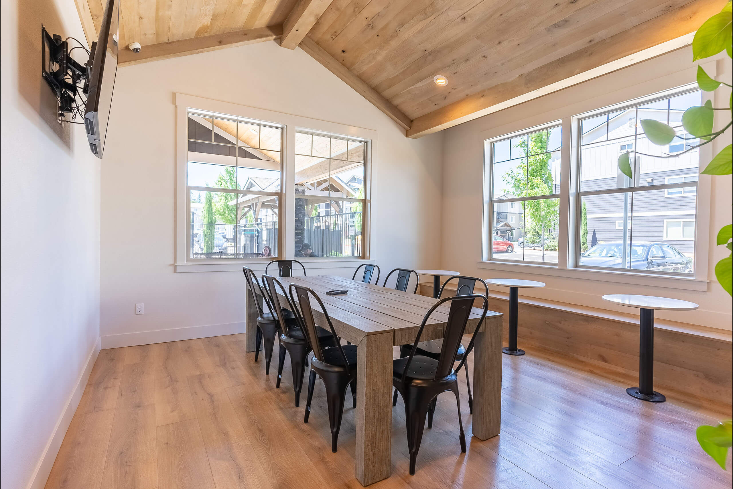 A room with a long table and chairs with a window in the background.