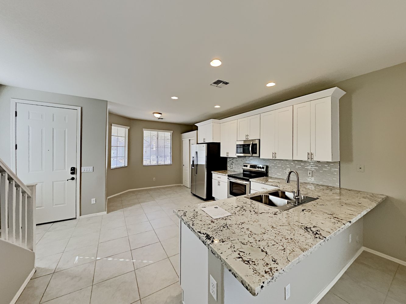 Kitchen with stainless-steel appliances, white cabinetry and easy to maintain tile flooring at Invitation Homes Phoenix.