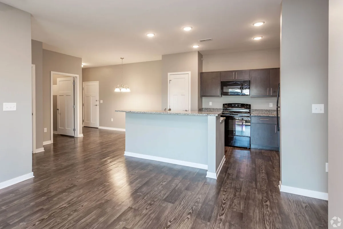 a renovated kitchen and living room with wood flooring at The Barclay Apartments, Altoona, IA
