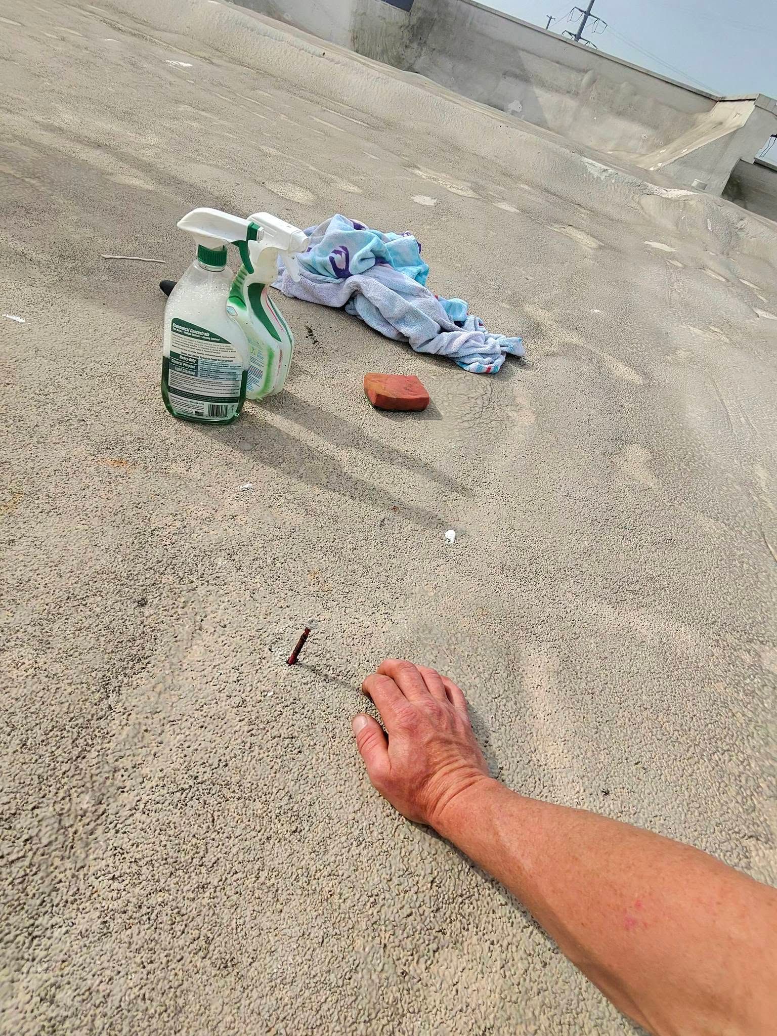 Technician inspecting a commercial spray foam roof with cleaning supplies and repair tools, identify 