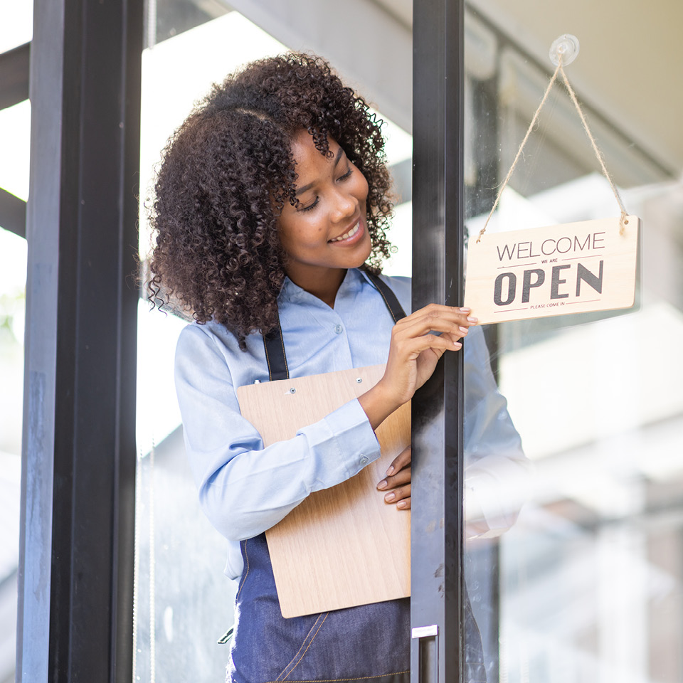 A small business owner flipping a sign to "Open"