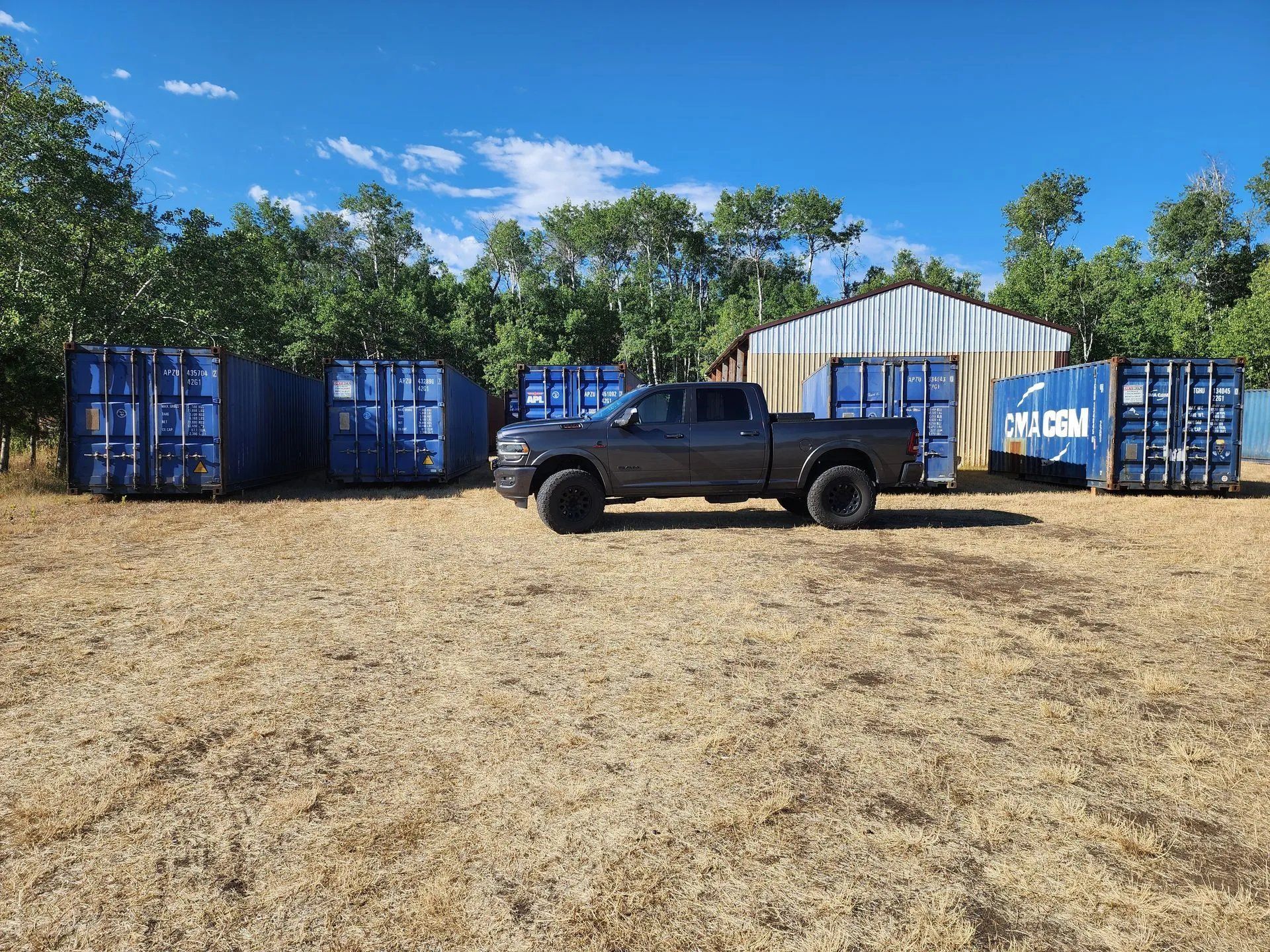 Pickup truck parked among multiple portable storage containers in outdoor yard, showcasing storage inventory options and accessibility for residential, commercial, and construction storage solutions in an organized storage facility.