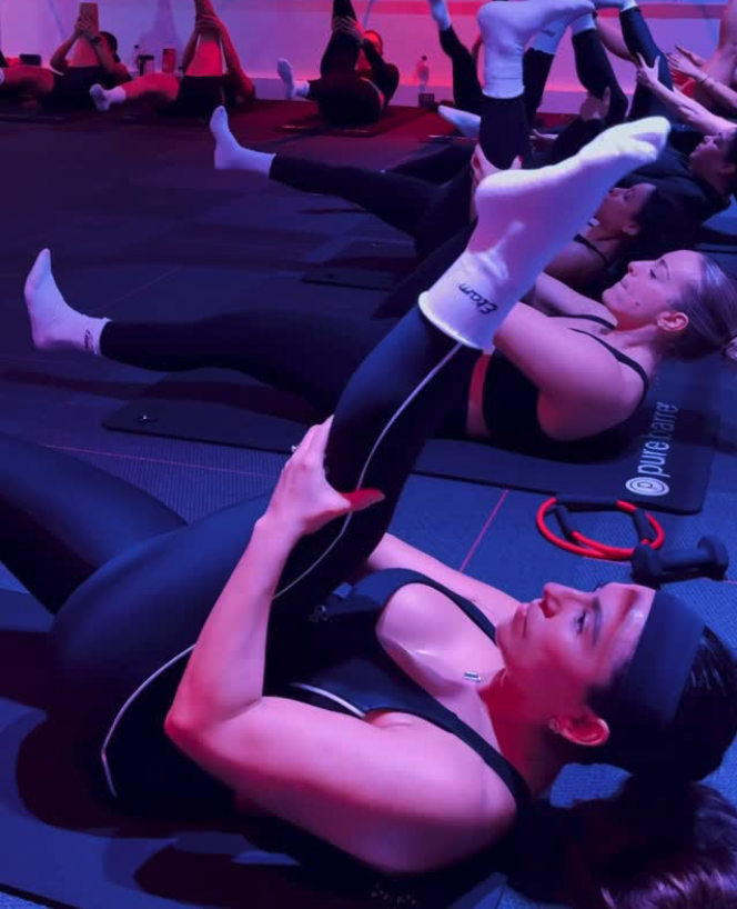 Group Pure Barre class in Aventura FL — members using resistance rings for low-impact core and leg toning exercises