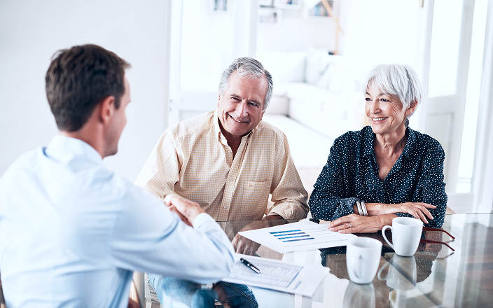 An older couple sitting down with their advisor at a table to review documents.