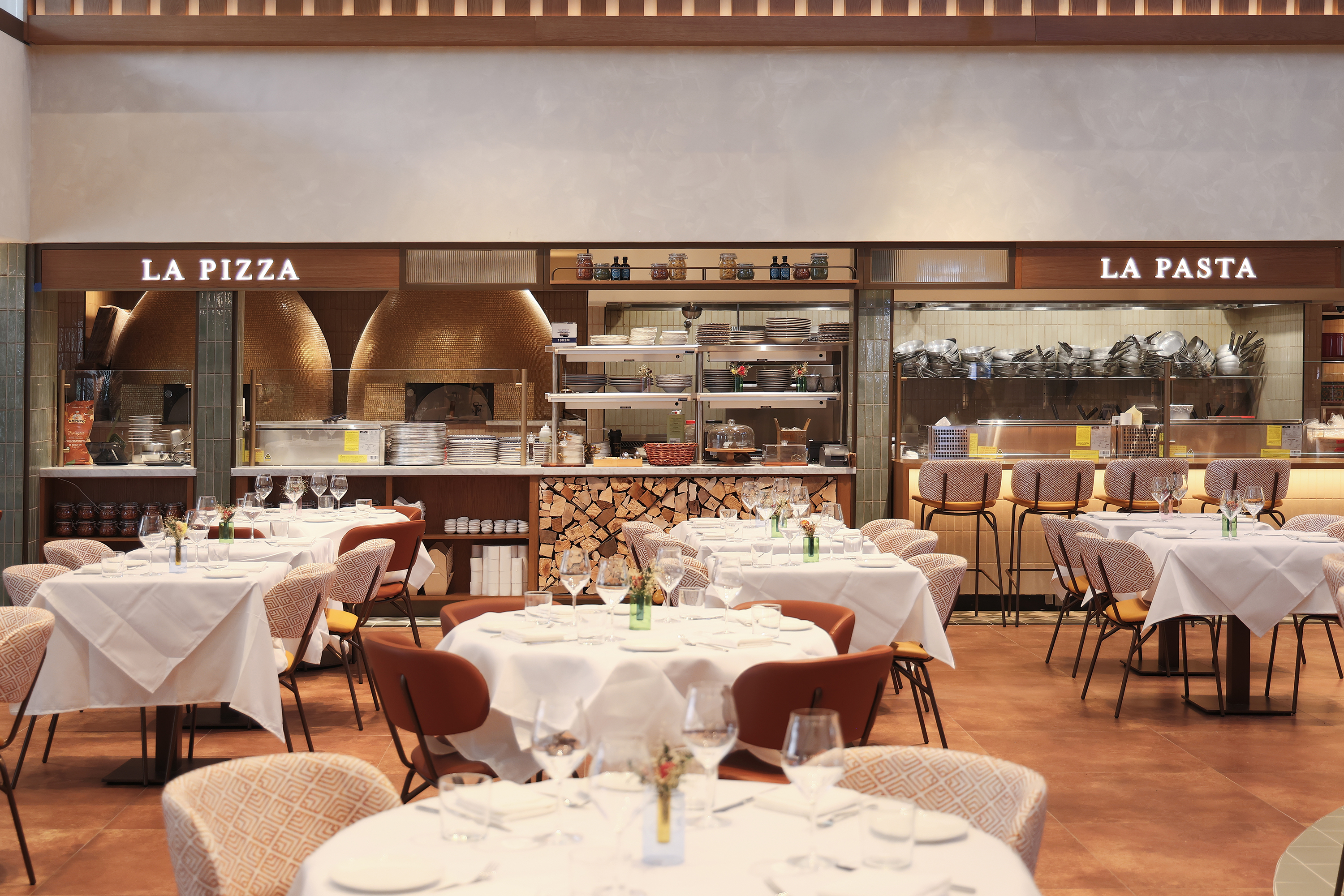 Open-kitchen dining experience highlighting handmade pasta and wood-fired pizza. 