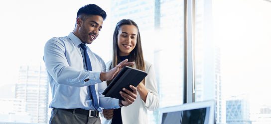 Two young professionals reviewing a notebook.