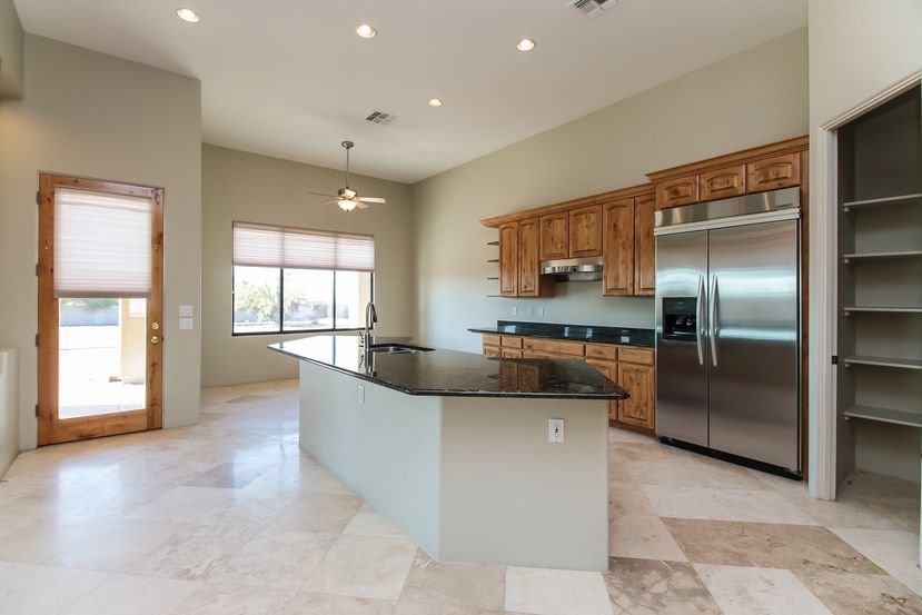 Kitchen with stainless-steel appliances, a spacious pantry and a large island at Invitation Homes Phoenix.