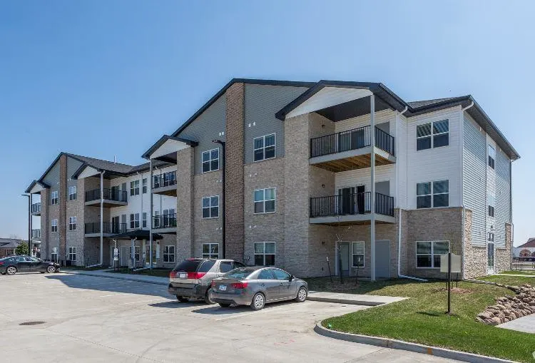 A large apartment complex with a parking lot in front at The Barclay Apartments, Altoona, IA