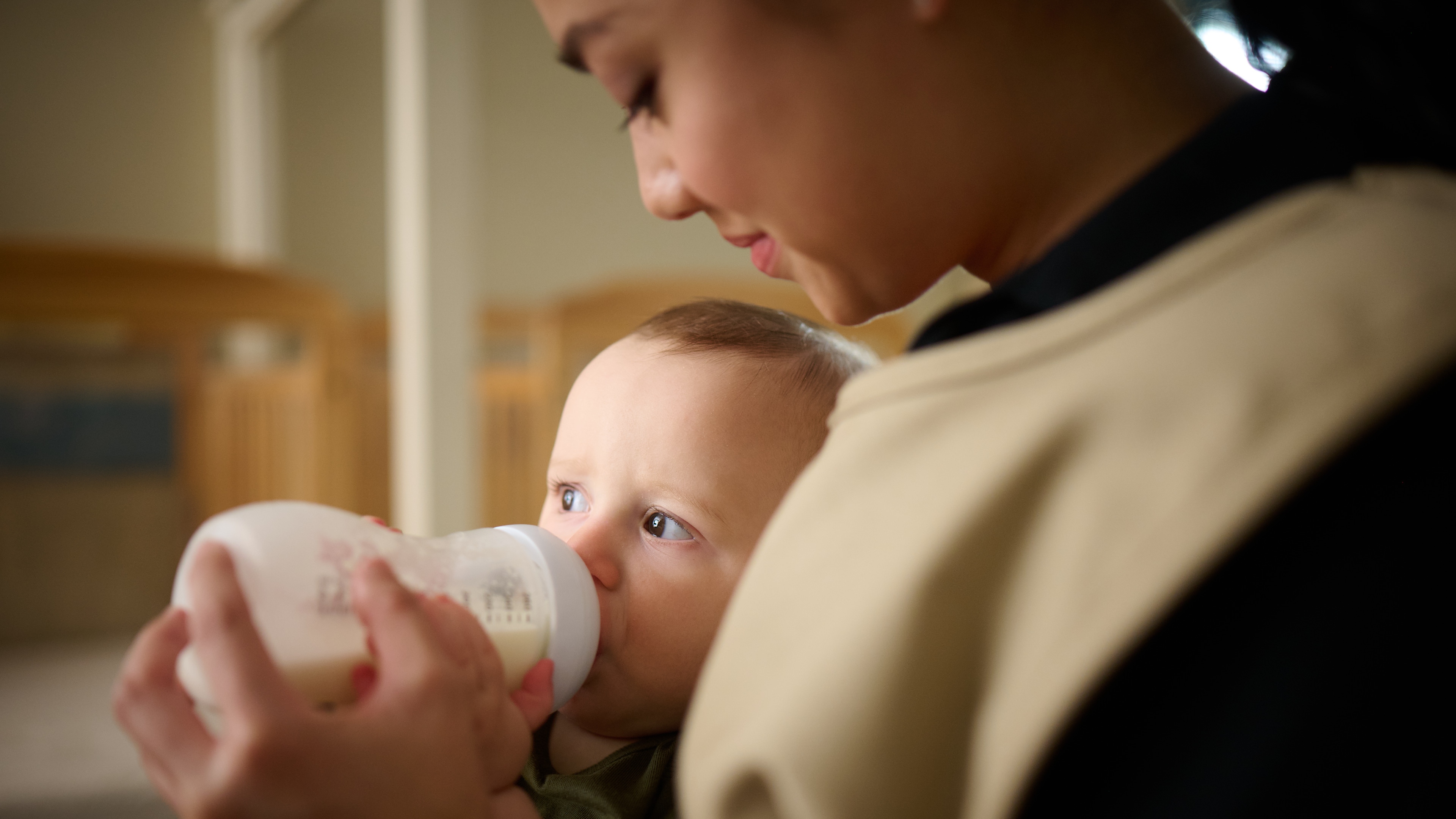 Primrose Schools infant care teacher bottle feeding newborn in nurturing early childhood classroom