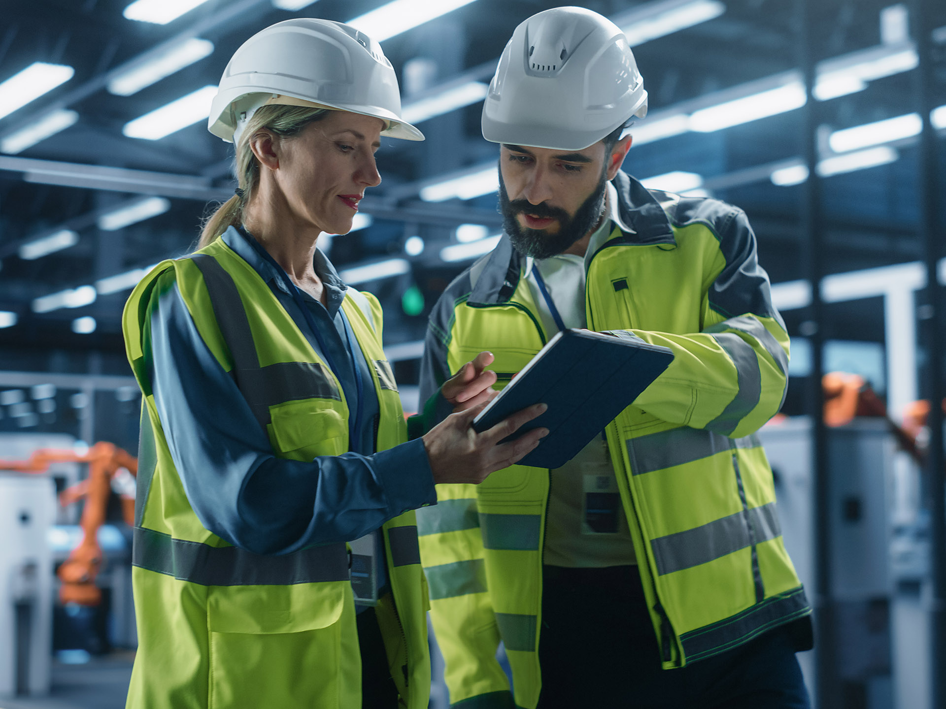 two warehouse workers looking at data on a tablet