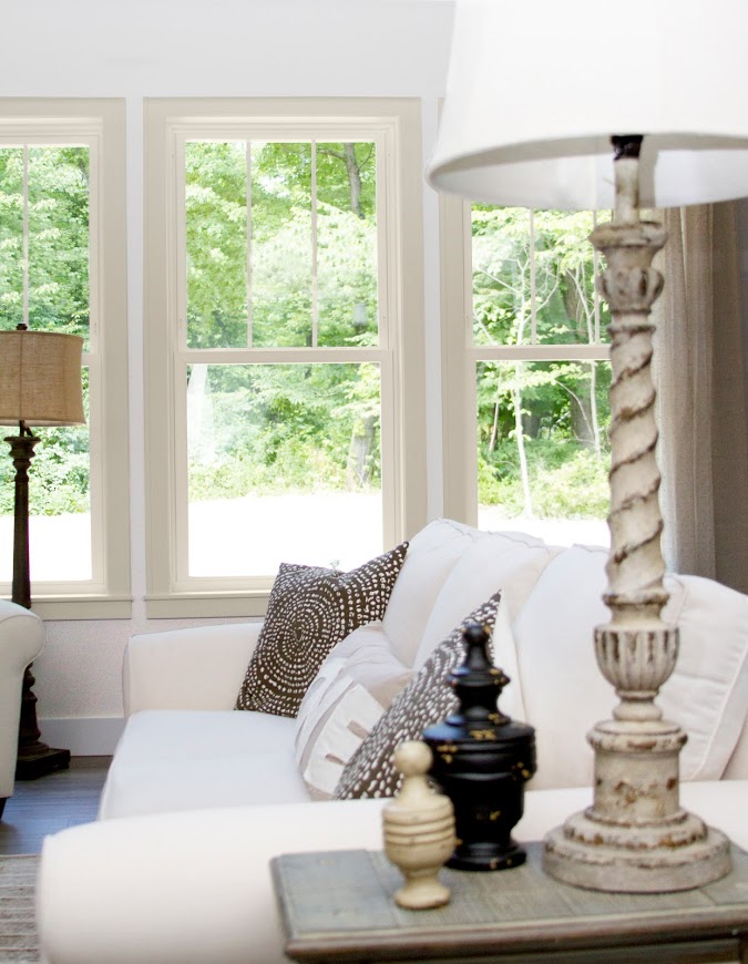 The EcoTek 3200 Series Double-Hung Windows in this living room bring in natural light and showcase the outdoor greenery. The beige frames blend seamlessly with the room's cozy, neutral decor, adding a classic yet modern touch that enhances the overall aesthetic and comfort of the space.