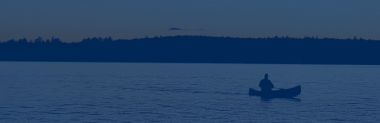 A canoer on the lake at dusk.