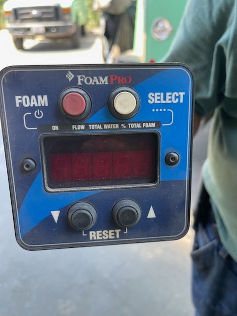 Close-up of a FoamPro control unit featuring foam and select buttons, digital display, reset controls, flow indicators, and rugged housing used with specialized firefighting or service vehicle equipment systems professionally.
