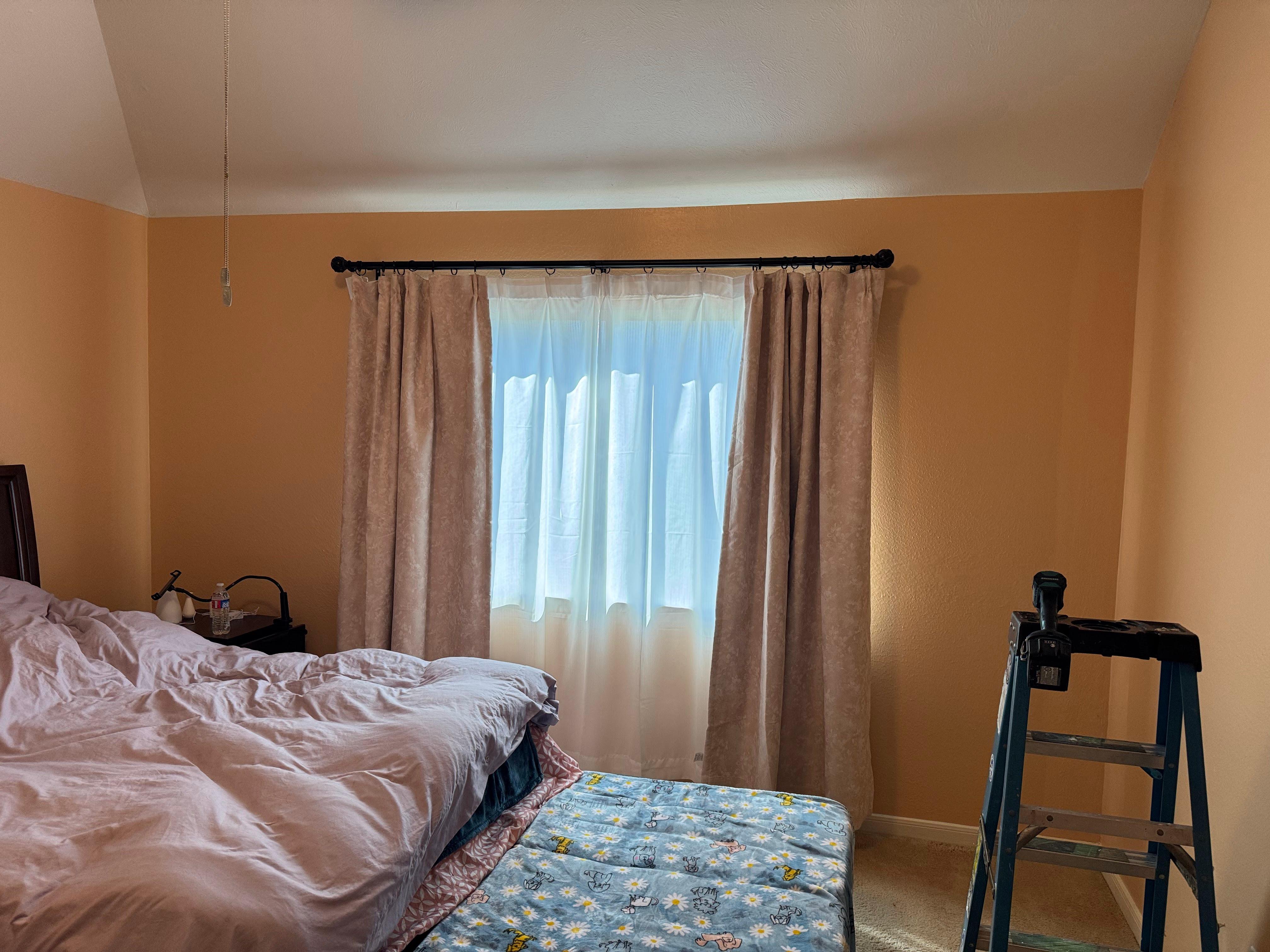Bedroom window with installed curtains and curtain rod in a residential home.
