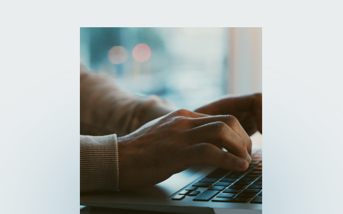 Close-up of an individual typing on their laptop keyboard.