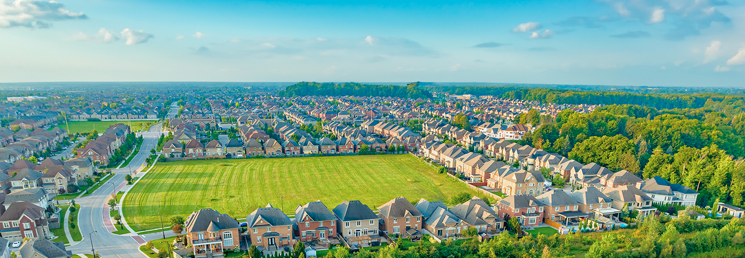 Aerial view of a suburban residential community filled with green space on a sunny day.