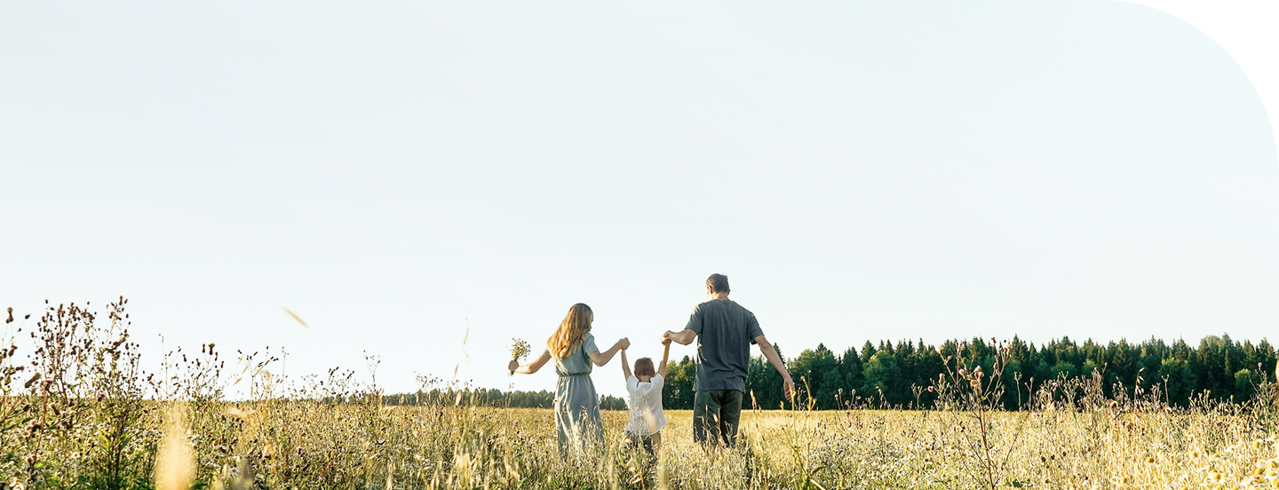 A family walking through a field hand in hand.