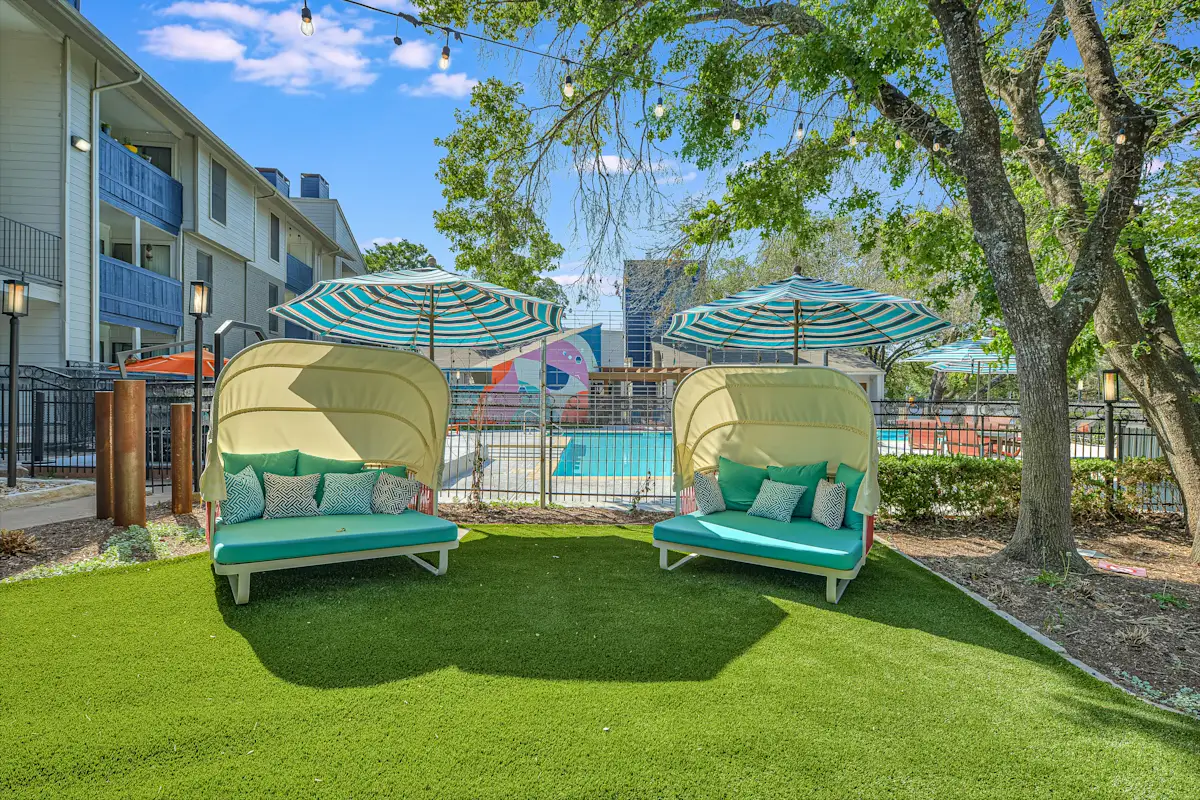 two lounge chairs with umbrellas in front of a pool
