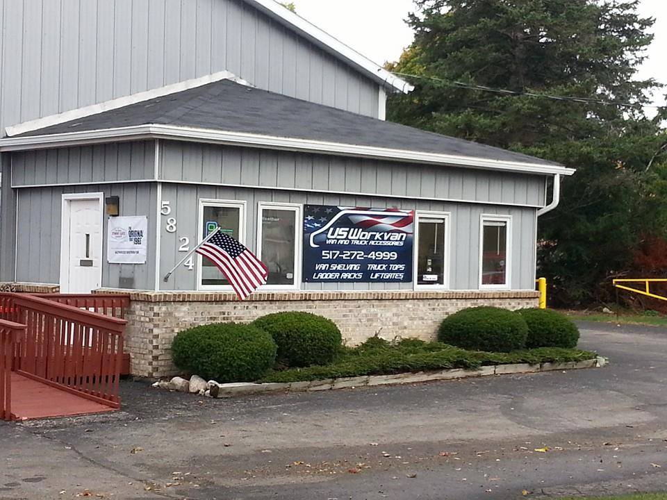 An image of the US Workvan storefront featuring company signage on the front window and an American flag waving on the right