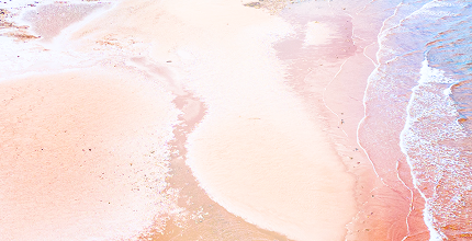 Aerial view of a sandy beach with gentle waves washing ashore.