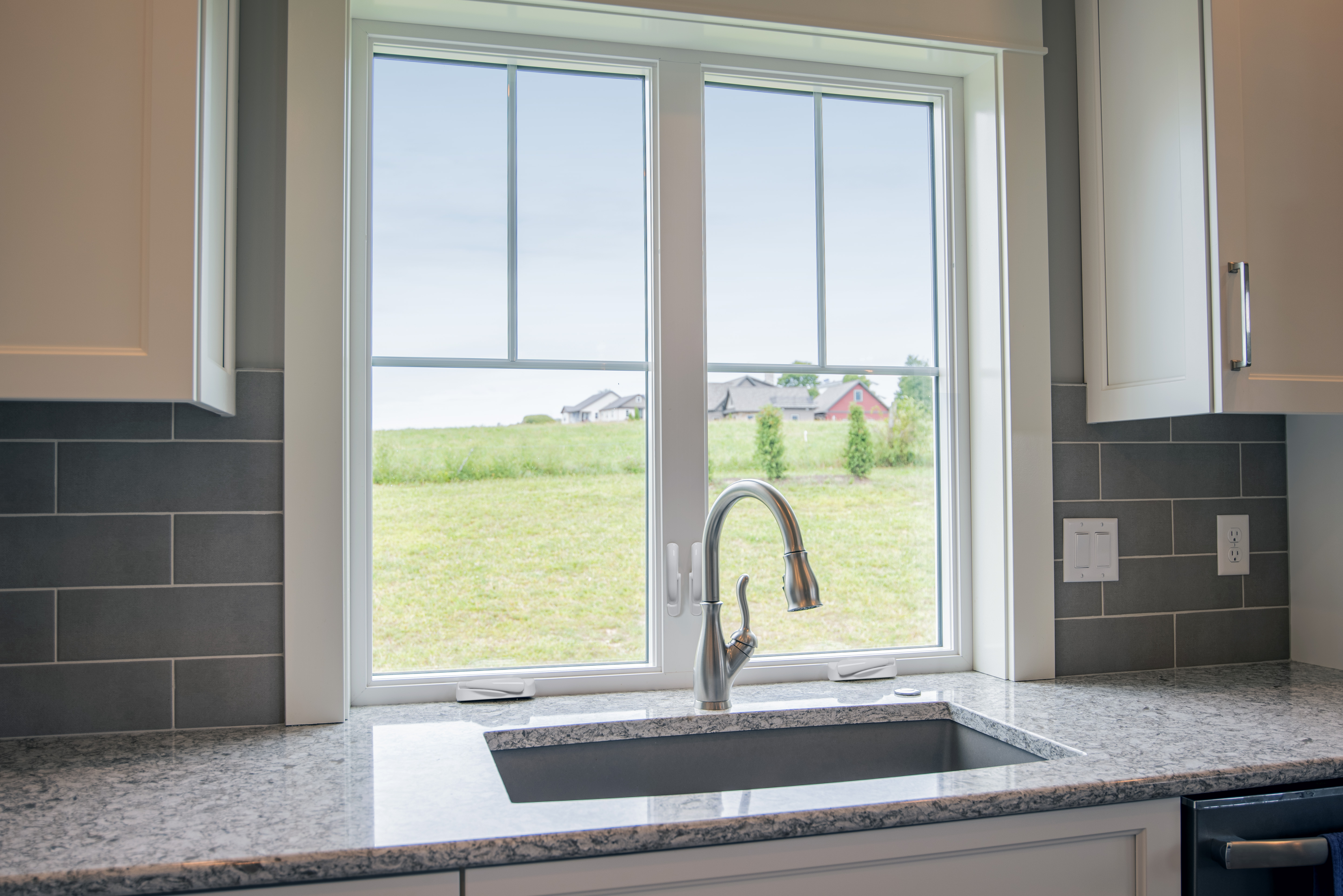 "The EcoTek 1200 - 2200 Series Casement Windows in this kitchen provide a clear view of the outdoors while allowing ample natural light to brighten the space. Their sleek design enhances the overall aesthetic, blending seamlessly with the granite countertops and modern cabinetry, adding a bright and open feel to the kitchen."