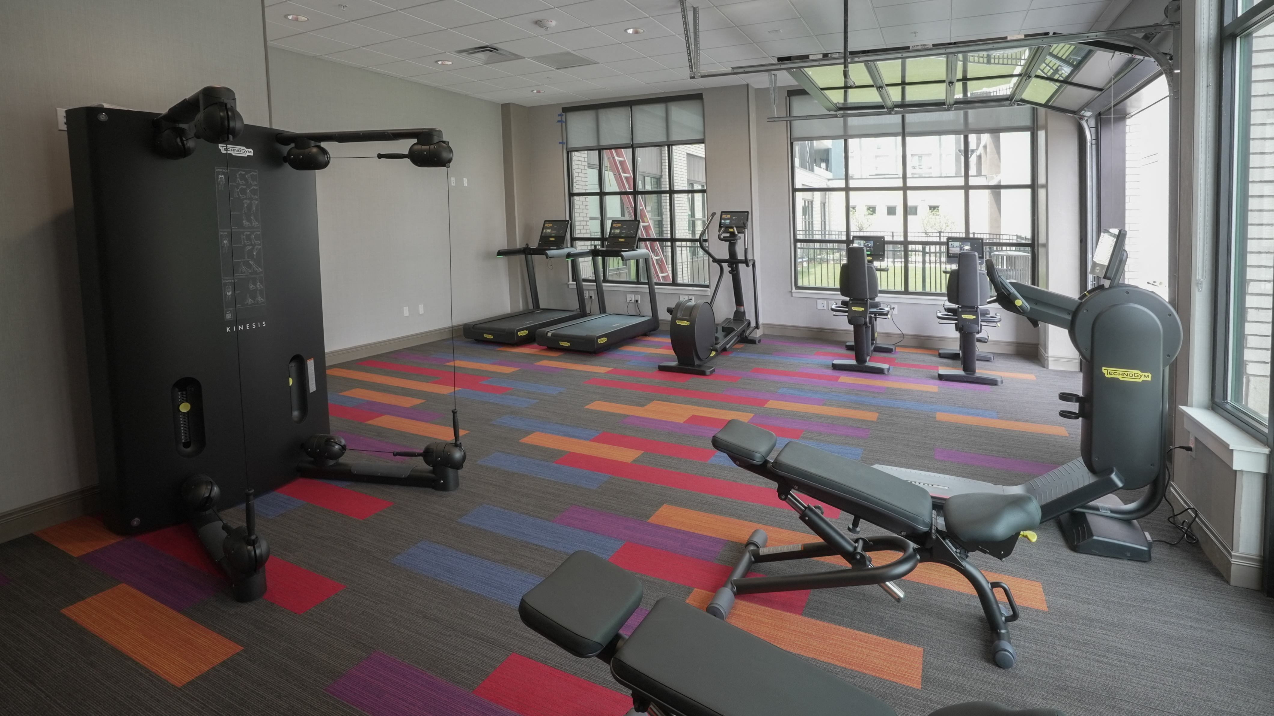 A gym with a variety of equipment including treadmills, weights, and exercise machines